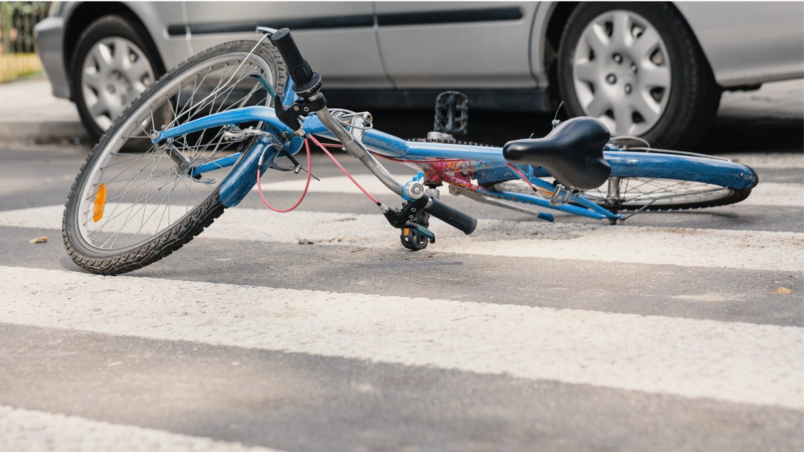A bicycle lying on the ground after a collision with a car, showing the aftermath of a bicycle accident.