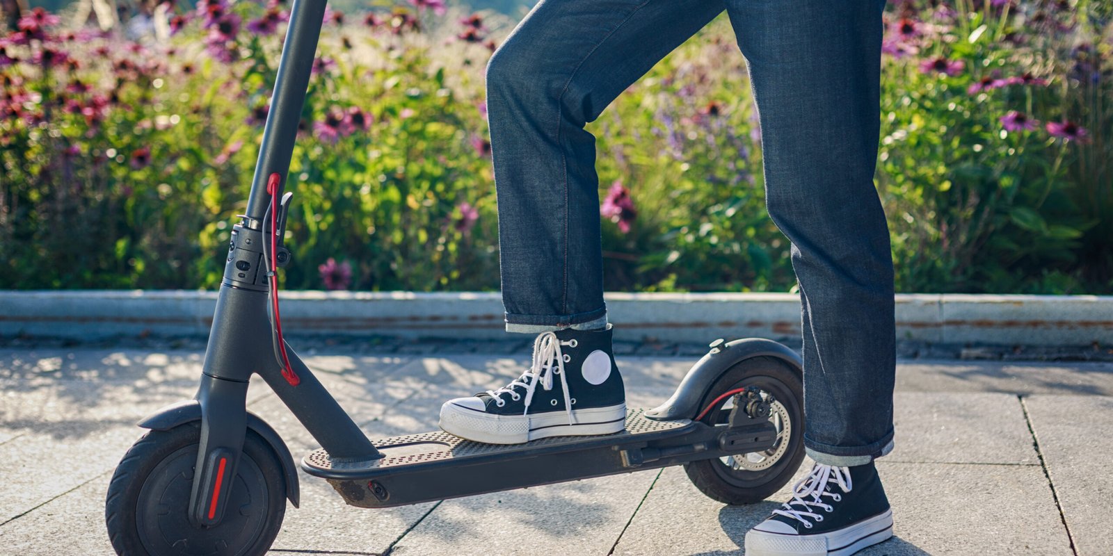 E-Scooter Rider Reflecting on Casual Injury A person standing next to an e-scooter in a park, wearing sneakers and blue jeans, reflecting on a scooter accident.