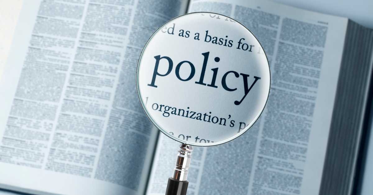 A close-up of the word "policy" under a magnifying glass, symbolizing the importance of understanding the terms and conditions in an insurance policy and how they relate to insurance liability limits.
