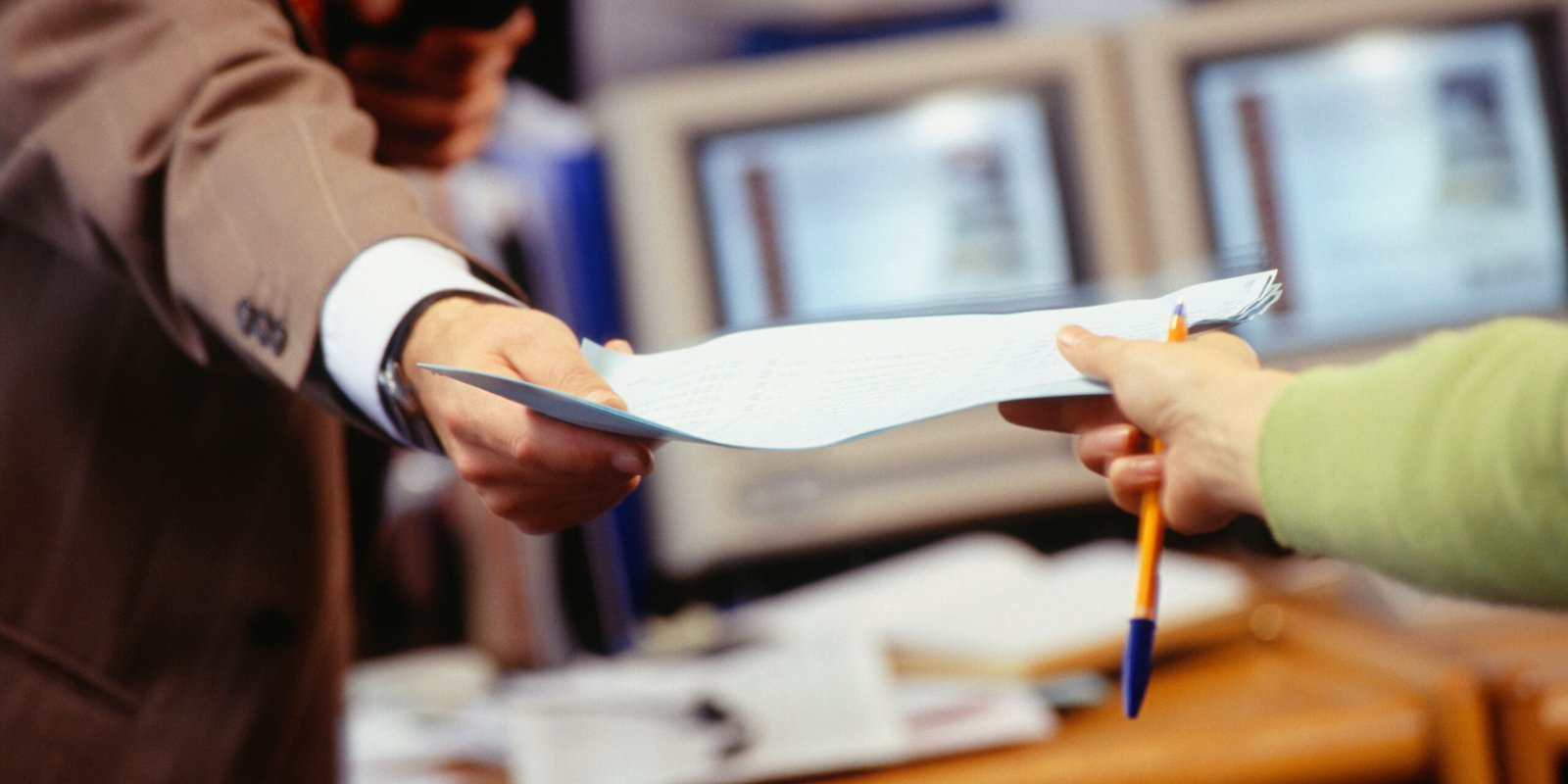 A person handing over personal injury paperwork during a consultation, preparing for their initial meeting with a lawyer.