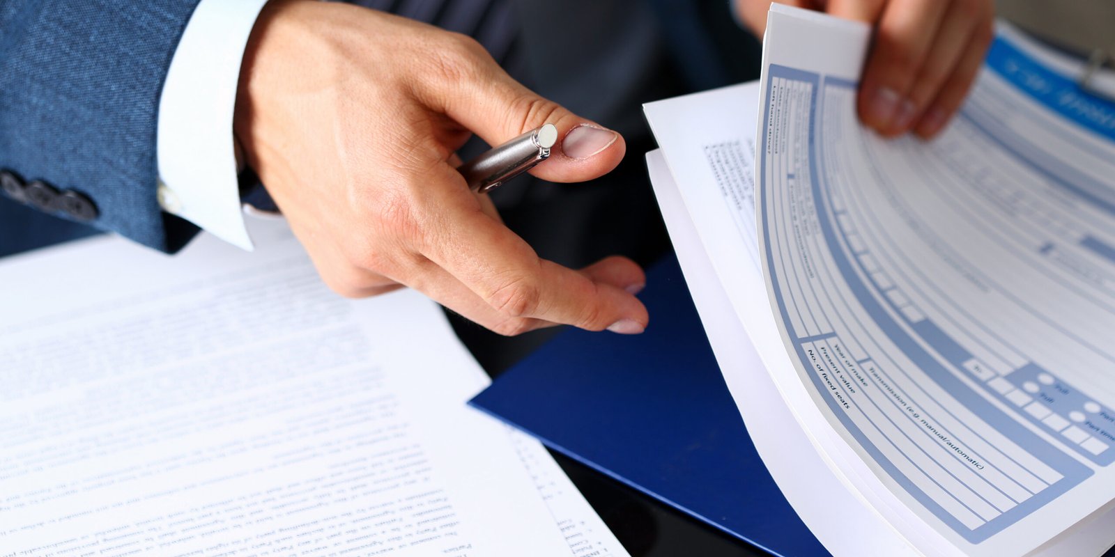 A close-up of a person in a suit reviewing insurance paperwork and forms after a car accident in California, highlighting the legal process involved.