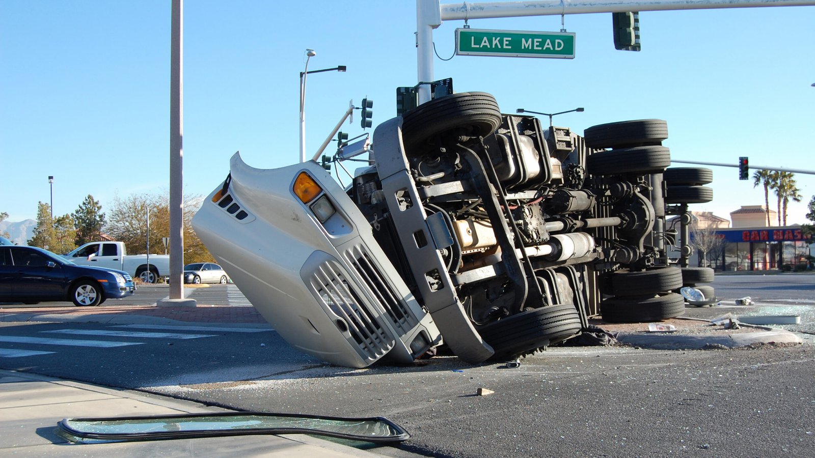 An overturned semi-truck lying on its side at an intersection with street signs visible, capturing the aftermath of a major truck accident in Southern California.