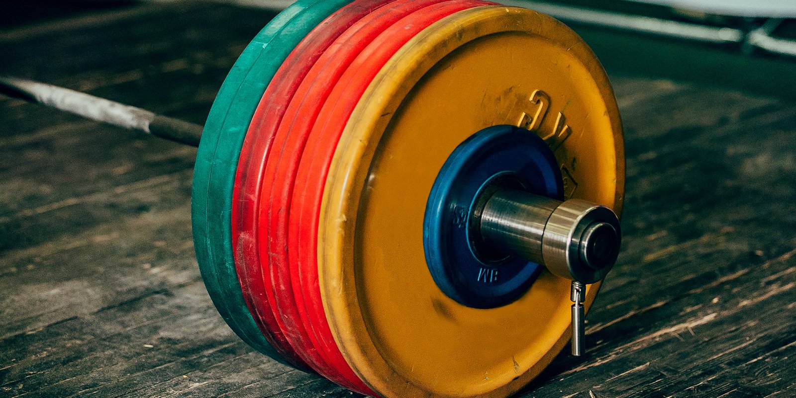 Close-up of a heavy barbell with colorful weight plates resting on a gym floor, symbolizing the strength and determination of The Powerlifting Lawyer.