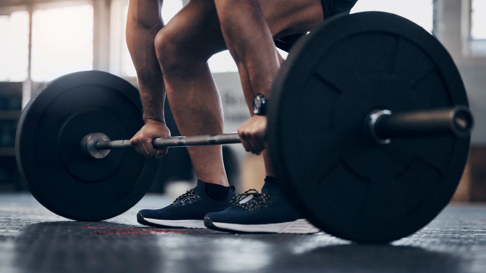 Focused athlete in a gym gripping a barbell, preparing for a deadlift, echoing The Powerlifting Lawyer’s commitment to hard work and winning results.